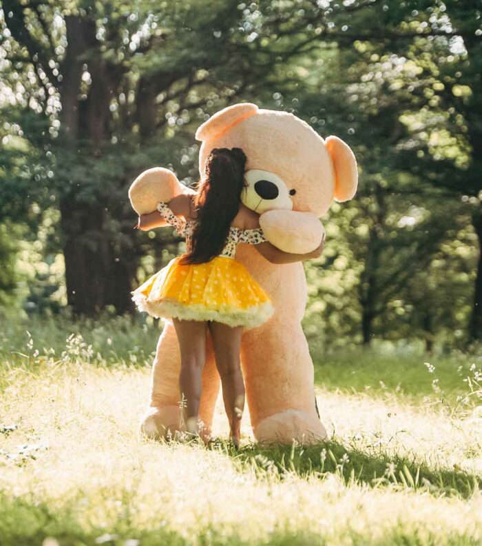 beautiful lady in dress dancing with giant teddy bear in forrest