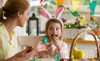 cut kid with easter bunny ears eating easter egg with mother