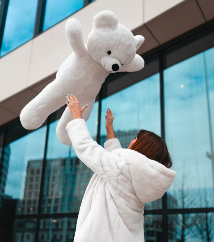 lady throwing white teddy bear in the air