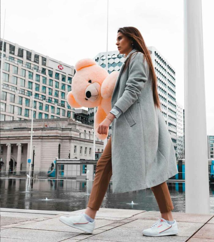smart sophisticated lady walking with teddy bear in city