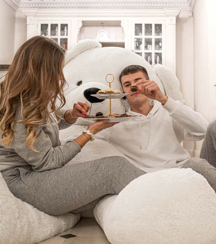 couple in luxury house eating food with giant white teddy bear