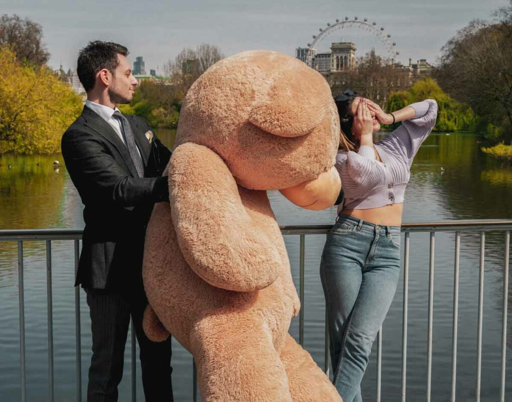 man gifting giant teddy bear as surprise to girlfriend