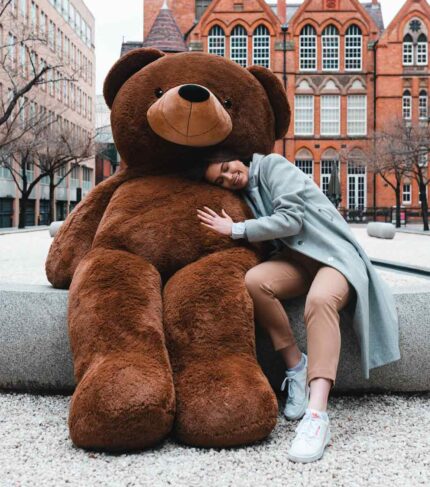 girl cuddling huge brown teddy bear