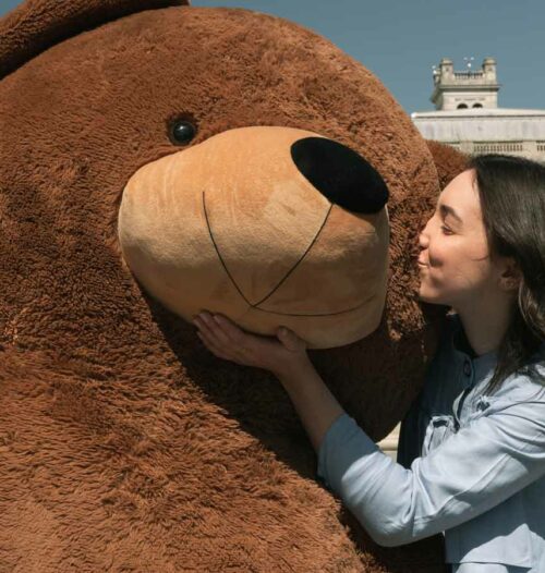 girl kissing huge brown teddy bear